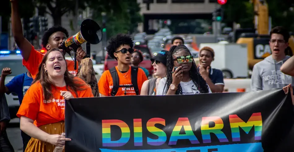 A group of protesters at a march holding a sign that reads "Disarm Hate".