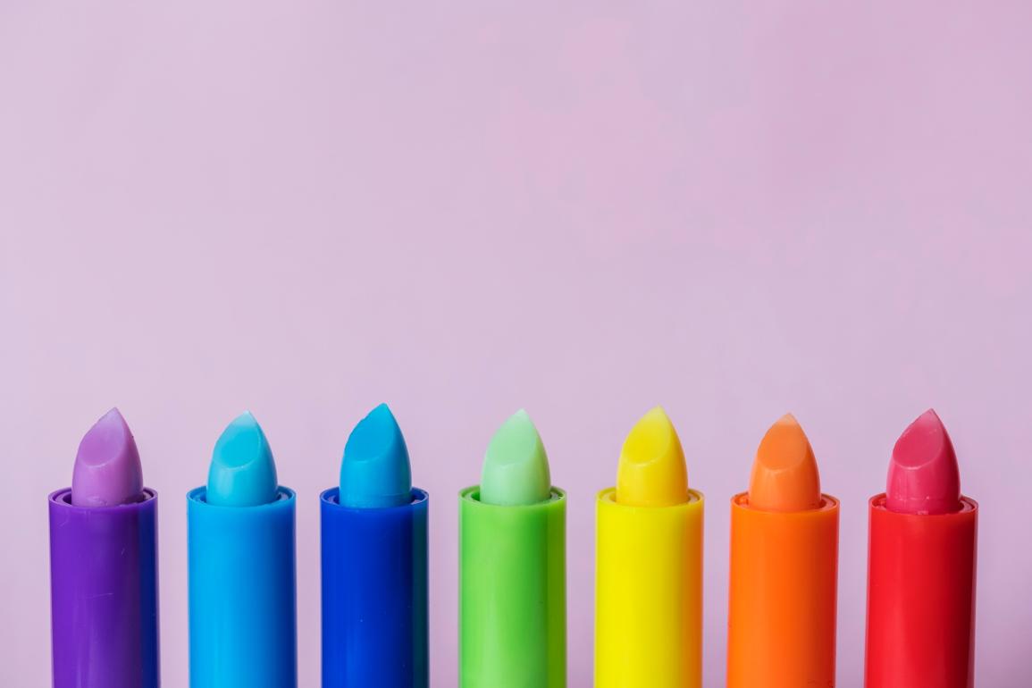 Row of multi-colored lipsticks creating a rainbow.